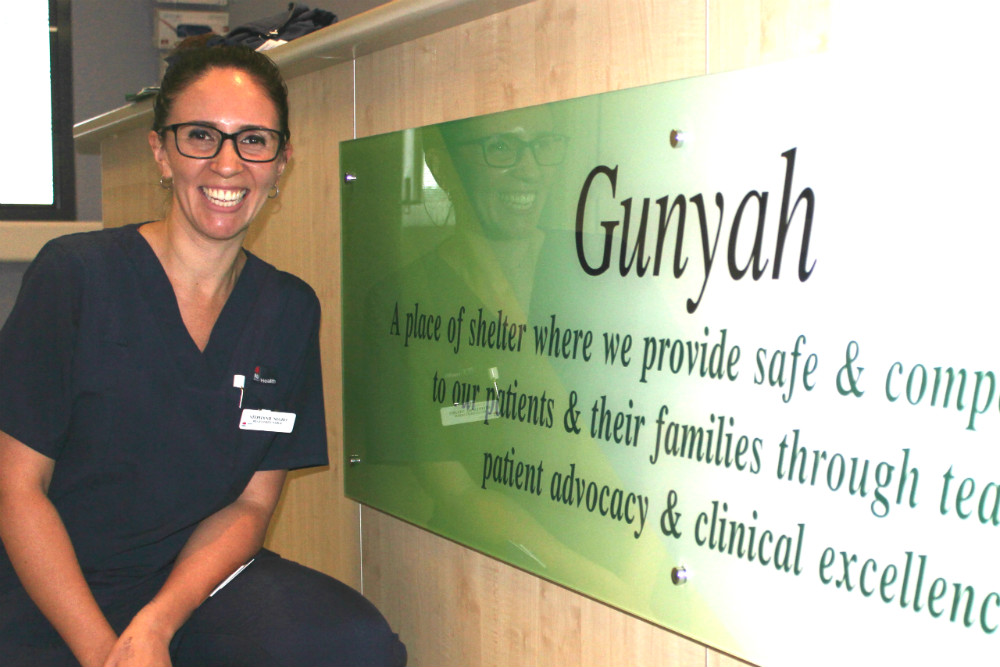 Nurse kneeling against ward sign