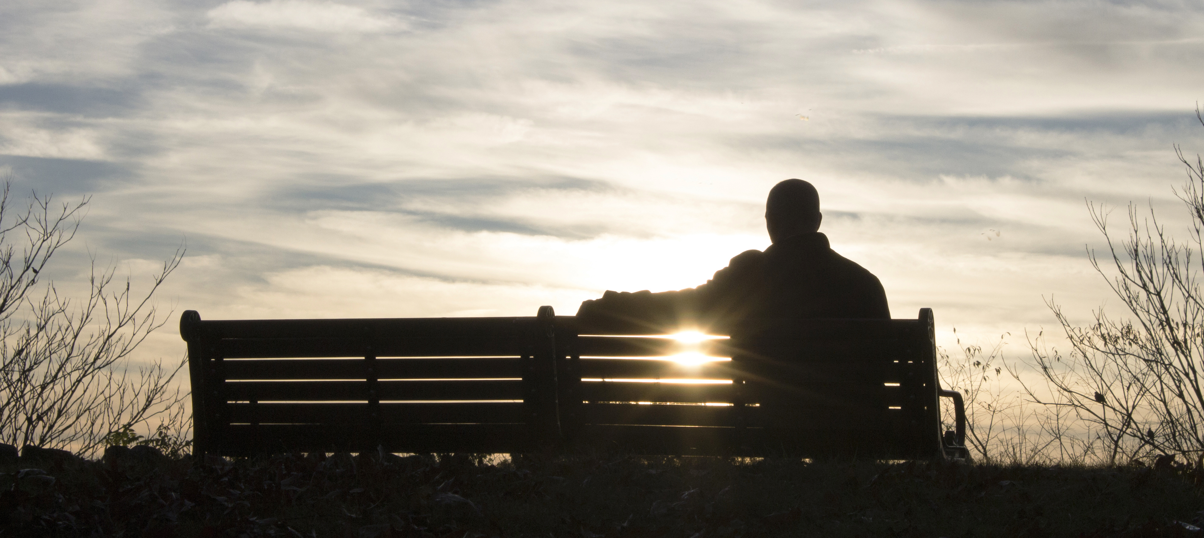 Silhouette of a man sitting on a park bench