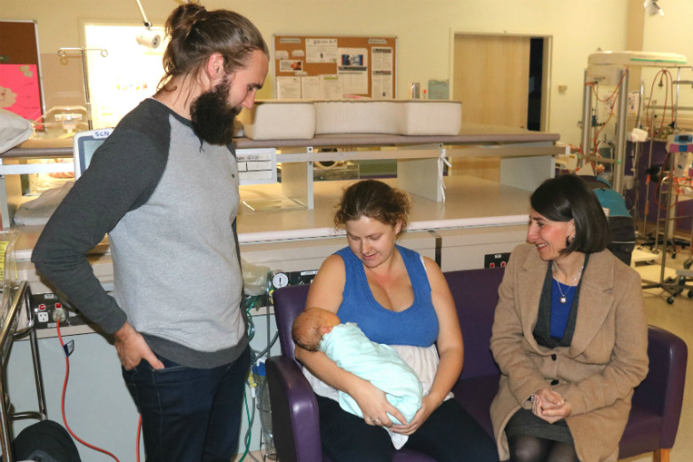 Male and two females looking at baby