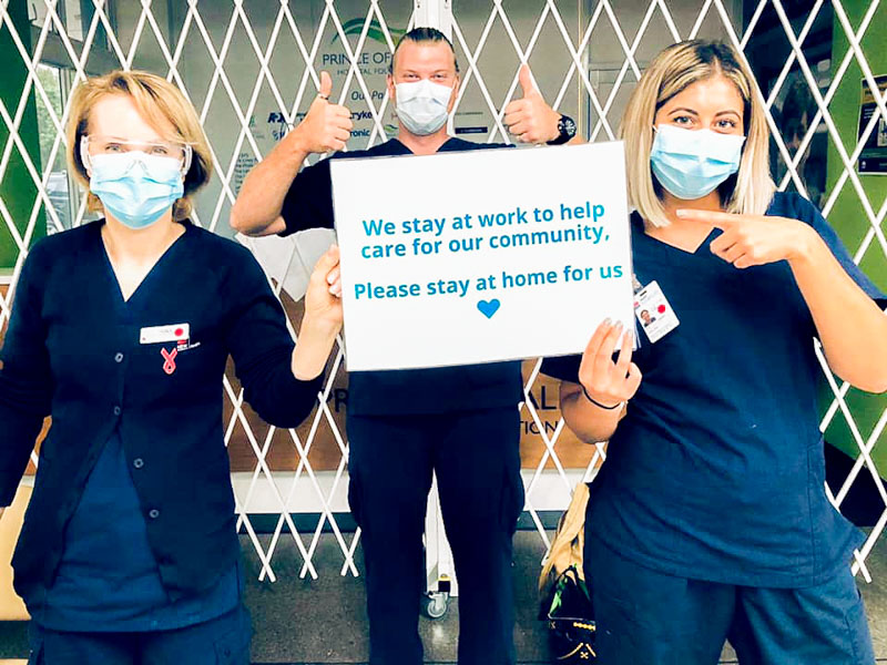 Prince of Wales Hospital staff holding a sign, asking the community to stay at home 