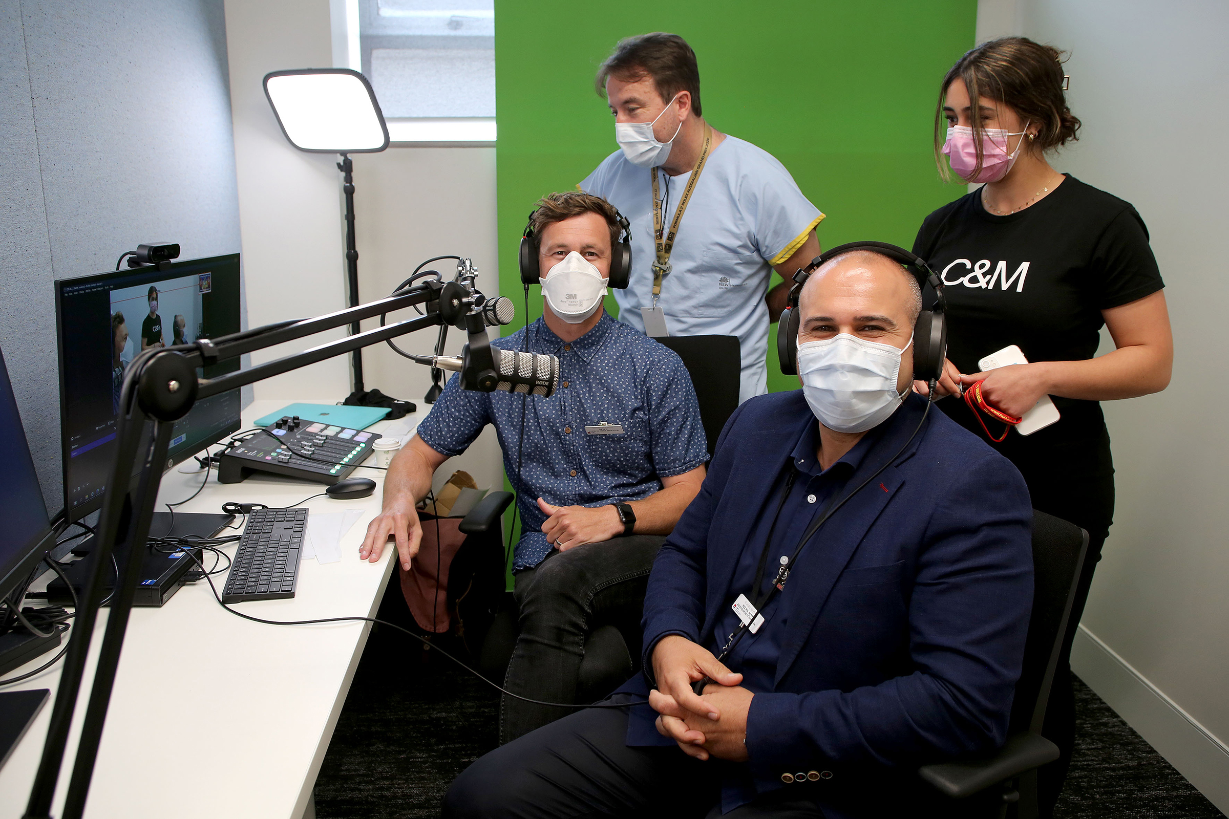 Staff sitting in a podcast room in front of a green screen