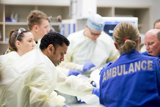 Several hospital staff surrounding critical patient