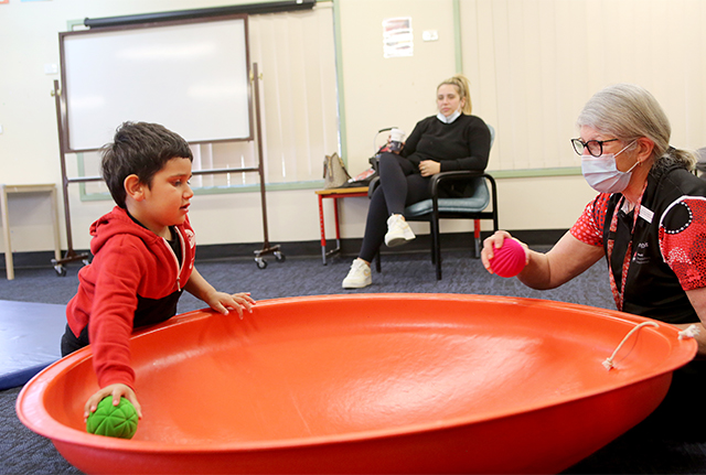 Child playing ball with health worker