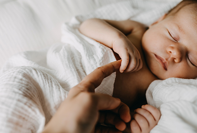 Baby holding mothers finger